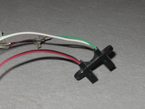 A roughly H-shaped black plastic sensor with wires leading to and from the tops of each vertical arm.