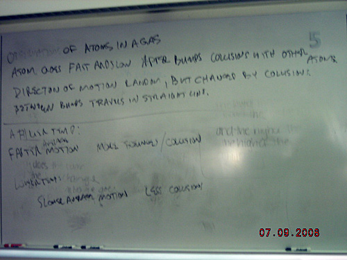 Notes written on a whiteboard about atoms in a gas.