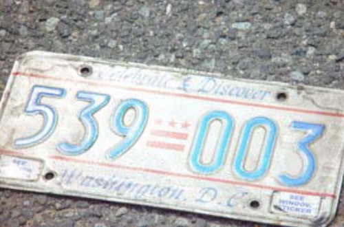A slightly battered Washington, DC license plate lying on the ground.