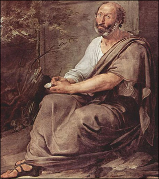 A balding, middle-aged man wearing a tunic and sandals, sits against a monument with a pen in his hand.