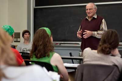 Paul Polak standing in front of the chalkboard, with seated students listening.