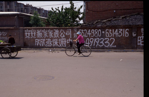 ͺһǽϵĹ档[Advertisements chalked on a wall in a residential district.]