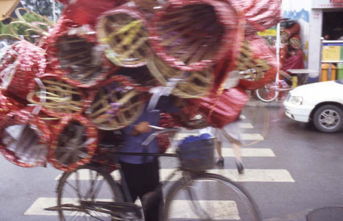 ͻ  ˡ[Man carrying a load of flower baskets on his bike.]