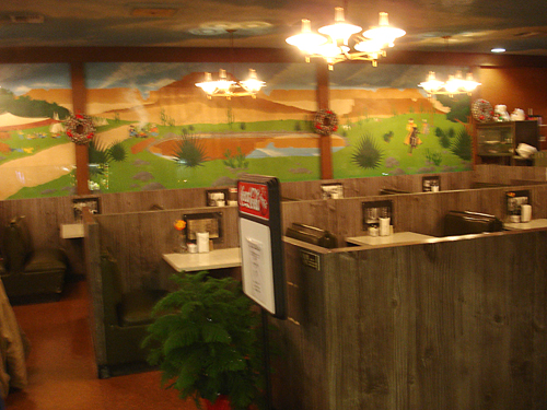 Restaurant booths fill the floor, in front of a pastoral mural.