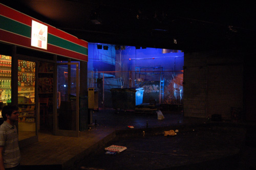 The back of the set is dimly lit in blue and shadows.
