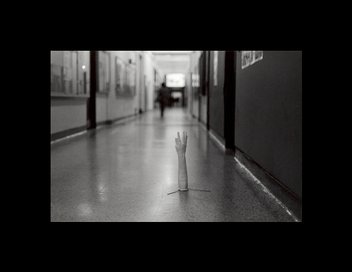 Photograph of a hand and forearm in a long hallway.