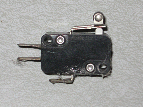A black plastic box with curved corners, a few extended metal leads, and a flexible metal arm.