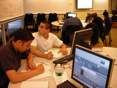 A group of students sits in front of computers doing calculations.