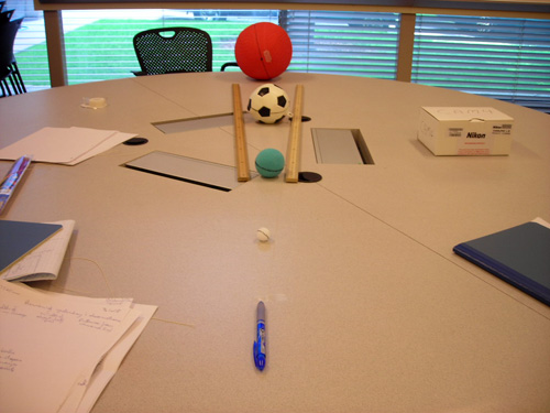 A small white ball, a larger green ball, a medium sized soccer ball, and kickball are lined up and measured.