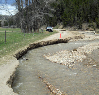Photo of a gravel road washed away by curving creekbed.
