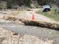 Photo of a gravel road washed away by curving creekbed.