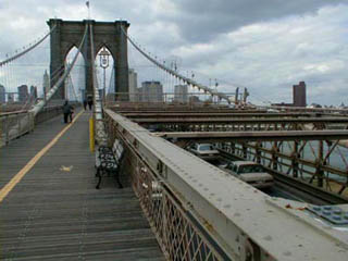 A photo looking down the middle of the pedestrian walkway on the Brooklyn Bridge.