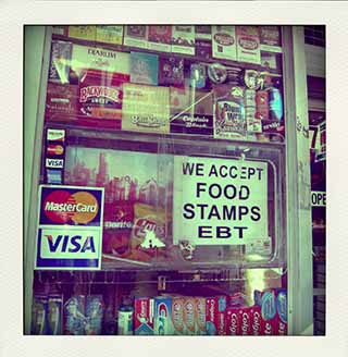 A deli window in Brooklyn with a sign that reads "We accept food stamps and EBT".