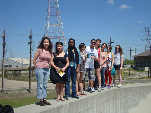 Nine students stand on top of a cement wall.