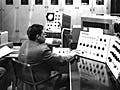 A photograph of two engineers sitting before a massive computer.