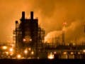 Towers of an industrial facility, with steam rising in the background.