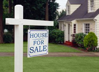 A photograph of a home with a for sale sign in front of it.