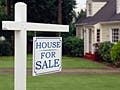 A photograph of a home with a for sale sign in front of it.