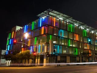 The exterior of a modern, glass-clad parking garage.