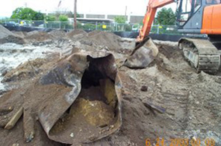 Image of a EPA cleanup site.  A backhoe is extracting a metal tank from the ground.
