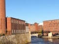 A river flanked by large brick buildings.
