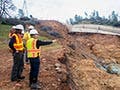 A photo of a group of construction workers standing on the edge of a ditch.