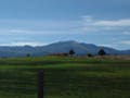 A landscape photo of farmland with mountains in the distance.