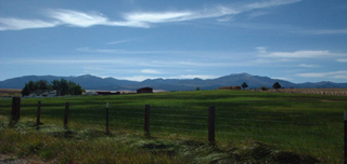 A landscape photo of farmland with mountains in the distance.