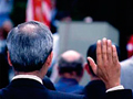 A photo behind a man raising his right hand during a naturalization ceremony.
