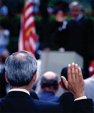 A photo behind a man raising his right hand during a naturalization ceremony.