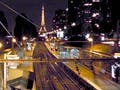 A photo of the Paris Metro tracks heading off to a lit Eiffel Tower on the horizon.