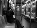 Black and white photograph of one rider on a mostly empty subway.