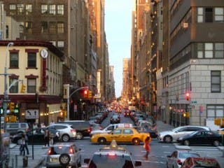 A city intersection with stoplights, automotive traffic, and pedestrians.