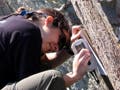 A student measuring the strike and dip of a rock face.
