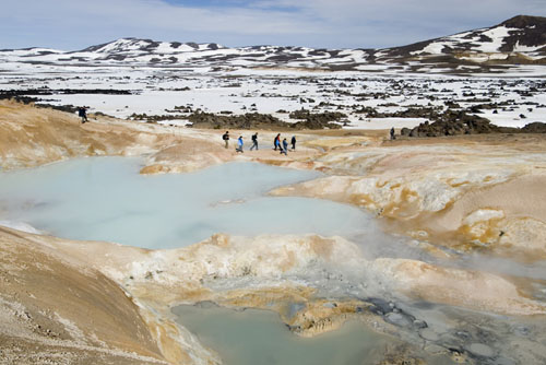 Students hiking between sulfurous geothermal springs and snow field.
