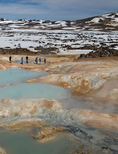 Students hiking between sulfurous geothermal springs and snow field.