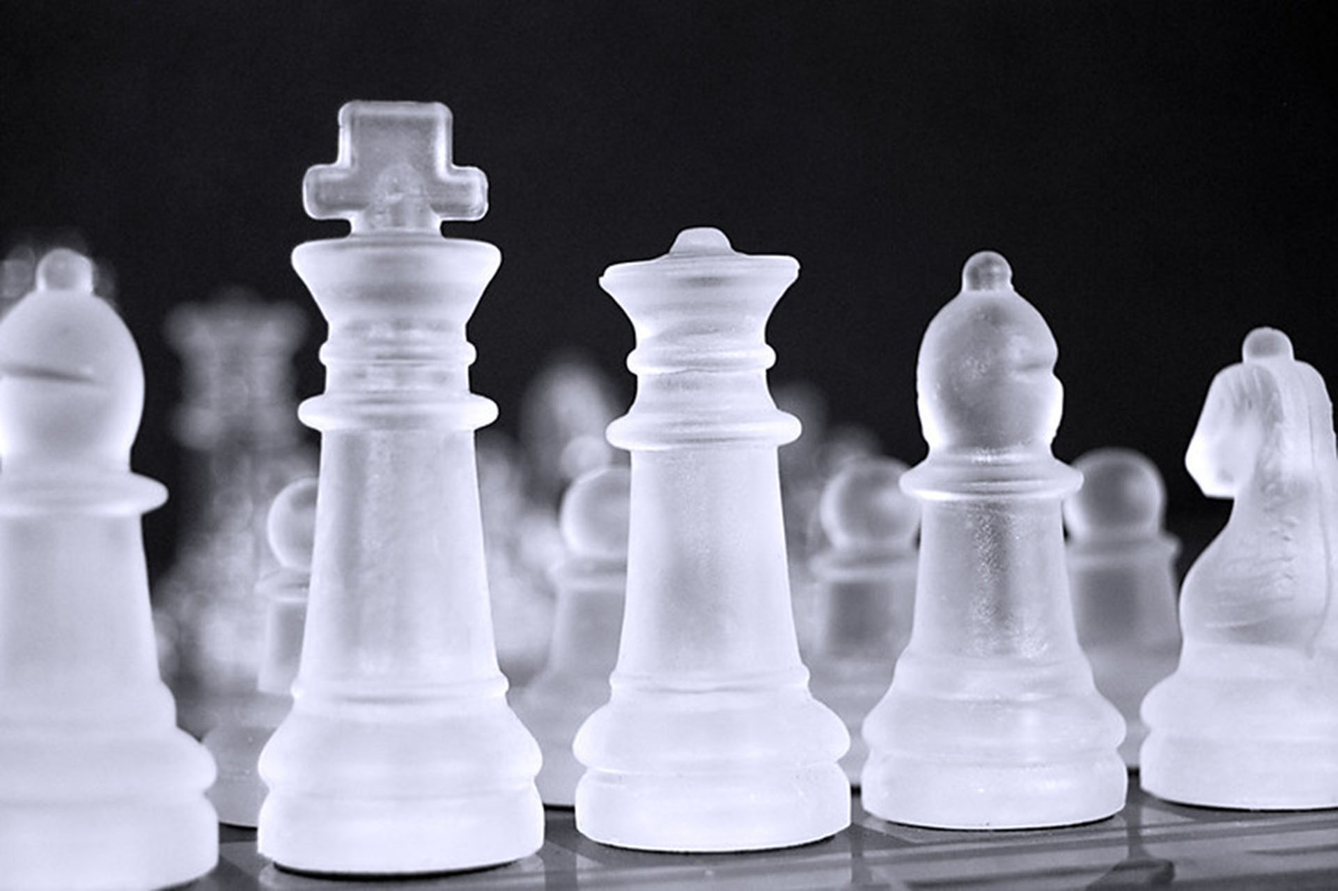 A close-up photograph of glass chess pieces on a board. 