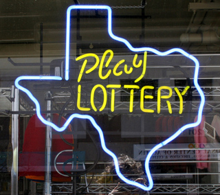 A photograph of a store window with an outline of the state of Texas in neon. Inside the outline are the words "Play Lottery."