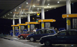 At night, cars fill up at a multi-lane gas station.