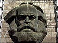 A huge bust of a bearded man sits in front of a multi-floored building.