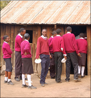 A photo of Kenyan teens wearing red school uniforms lined up outside.