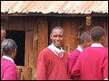 A photo of Kenyan teens wearing red school uniforms lined up outside.