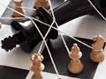 Several chess pieces hold down and oversized king with ropes.