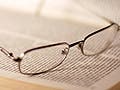 A pair of glasses sitting on an open book.