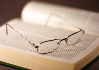 A pair of glasses sitting on an open book.