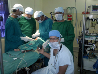 A team of doctors wearing scrubs and masks operate on a small child.