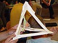 A photograph of a student-constructed egg protection device.  The device consists of a paper pyramid with an egg suspended within. 