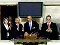 Seven people standing in front of the podium above the trading floor of the New York Stock Exchange.