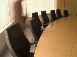 A photo of a person dashing across a typical boardroom.