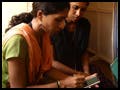 A female health worker logs data on a device as two others look on.